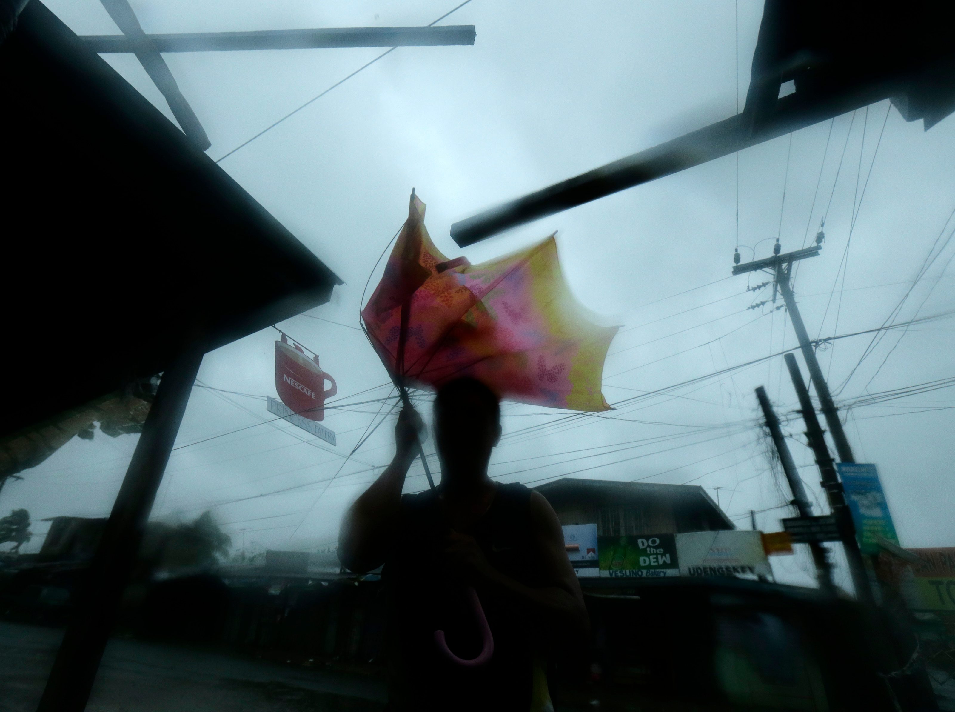 Warga Munoz, Nueva Ecija memegang payung yang tertiup angin kencang Topan Lando (Koppu) setelah mendarat.  Foto oleh Francis Malasig/EPA 