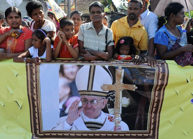 AWAITING FRANCIS. Sri Lankan Christians hold paraphernalia bearing the portrait of Pope Francis as they wait for his arrival in Colombo on January 13, 2015. Lukruwan Wanniarachchi/AFP