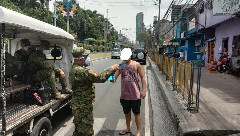 SOLDIERS' PATROL. A Philippine Army reservist gives a Mandaluyong City pedestrian a face mask. Photo from the Mandaluyong CDRRMO 